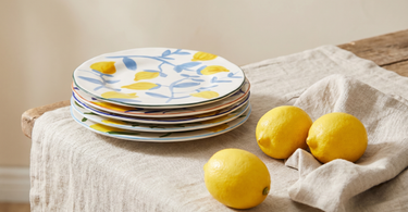 Stak af citron-tallerkener fra &Klevering på en hørdug med friske citroner