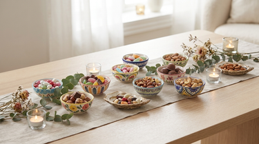 Små farverige keramikskåle med slik og nødder på et festbord