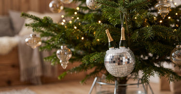 Champagne ornament i glas fra Kersten på en nordmannsgran med lyskæde