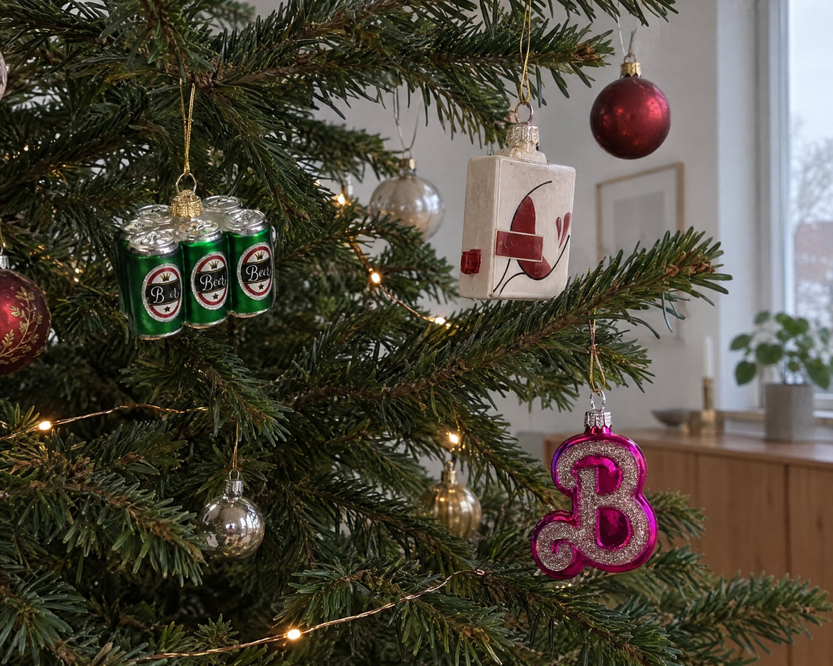 Lustige Christbaumkugeln aus Glas in Form eines Sixpacks, eines Weinkartons und eines pinken B am Weihnachtsbaum